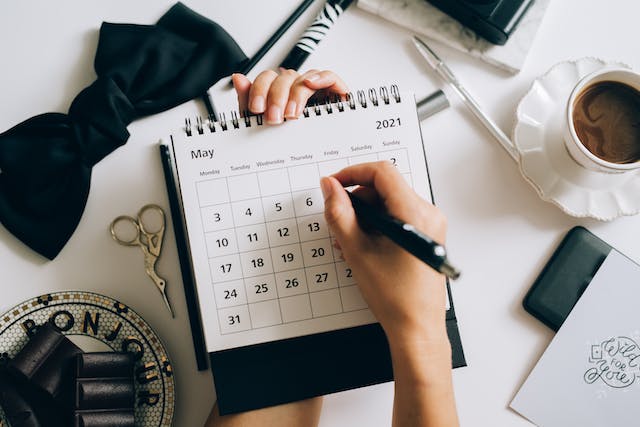 Uma foto de alguém marcando a data em um calendário com uma caneta esferográfica.