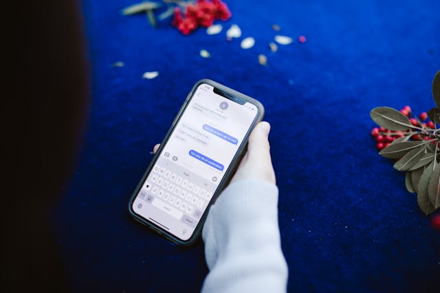 Uma pessoa segurando um telefone com mensagens de texto em azul e branco em um fundo branco.