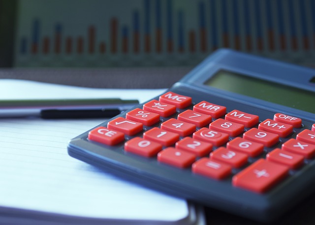 Uma calculadora em uma superfície branca com um gráfico analítico borrado em segundo plano.