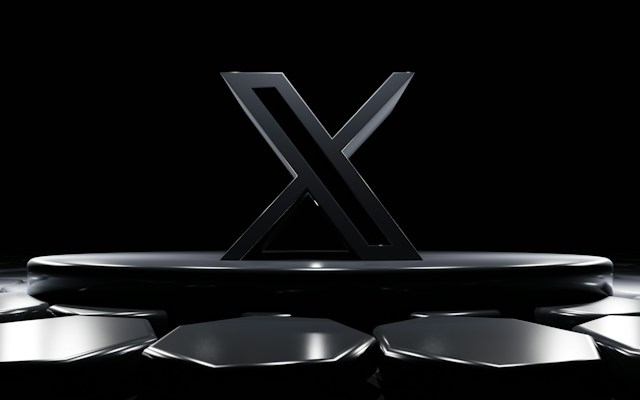 Ein Bild eines schwarzen X-Logos auf einer kreisförmigen Plattform auf schwarzem Hintergrund.