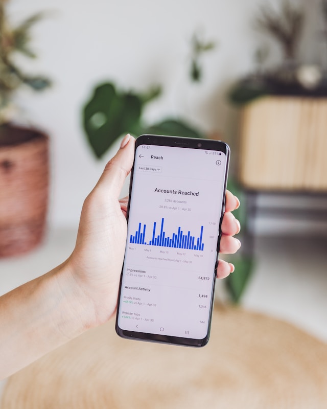 Una persona sostiene un teléfono que muestra el gráfico de alcance de una cuenta social
