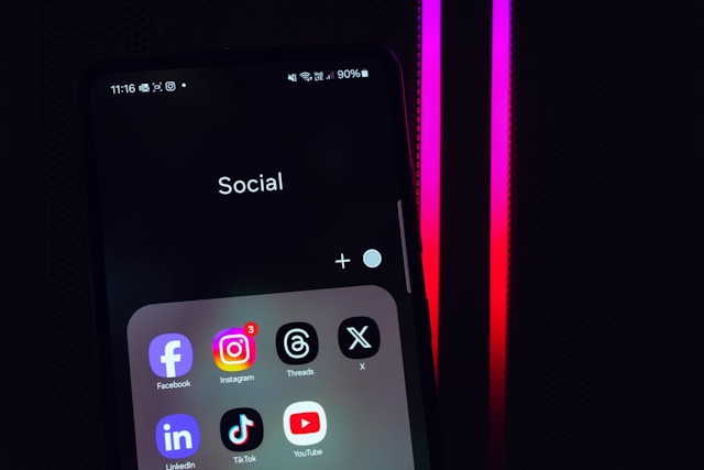 Dossier d'applications de médias sociaux affichant les applications X et Threads sur un smartphone.