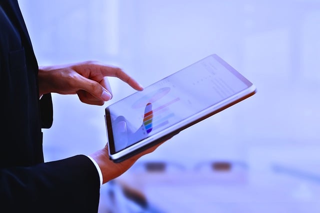 Seseorang yang mengenakan setelan jas mengetuk grafik dan bagan analitik pada tablet digital.