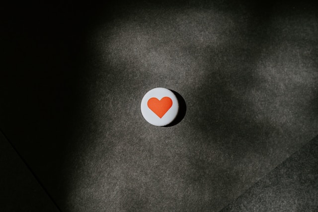 Un'immagine dell'emoji "like" su un pulsante bianco su una superficie nera.