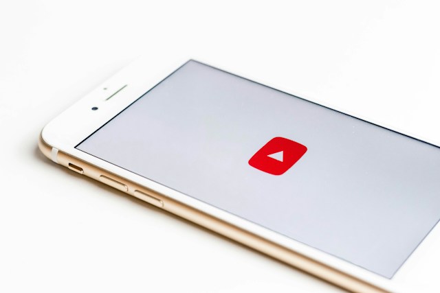 Una fotografia di un telefono bianco che mostra il logo di YouTube su uno schermo bianco.