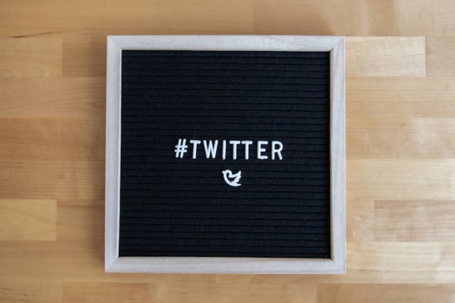 Una bacheca nera con lettere bianche che scrivono "#TWITTER" sopra il logo dell'uccello di Twitter.