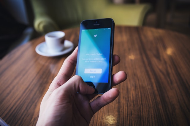 Uma pessoa segura um telemóvel e mostra a página para criar uma conta Twitter ou X.