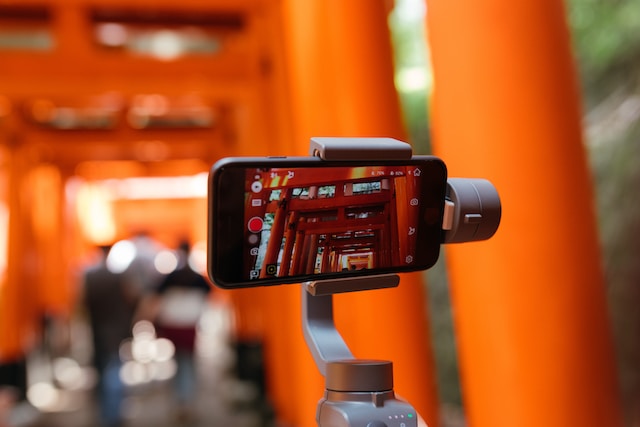A picture of a mobile phone making videos from a selfie stick.